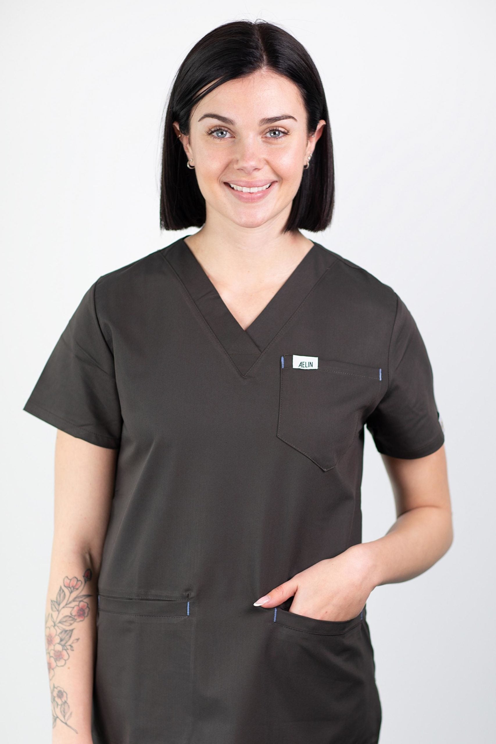 Femme en tunique médicale gris foncé de qualité avec col en V et poche